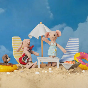 Rabbit figurine Milo playing a red guitar during a gentle day by the shore.