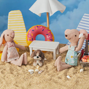 Close-up of Kivvi Tales puppy and dolls relaxing with colorful miniature beach accessories.