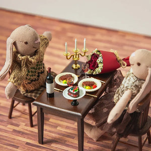 Dollhouse candlelight dinner scene showing a Valentine’s dining setup with table, chairs, candles, wine, and dessert for a 1:12 scale dollhouse
