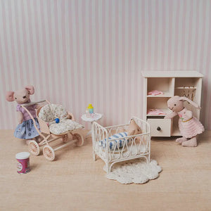 dollhouse nursery scene with crib stroller wardrobe and miniature figures in a soft pink 1:12 scale storytelling setup.