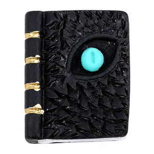 Miniature dragon eye spell book with turquoise eye, textured black cover and gold-tone spine details