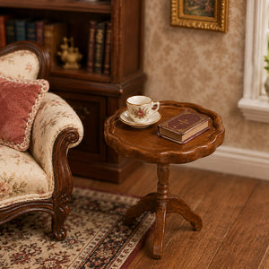 Brown scalloped side table styled with a teacup and book beside an armchair in a classic miniature living room