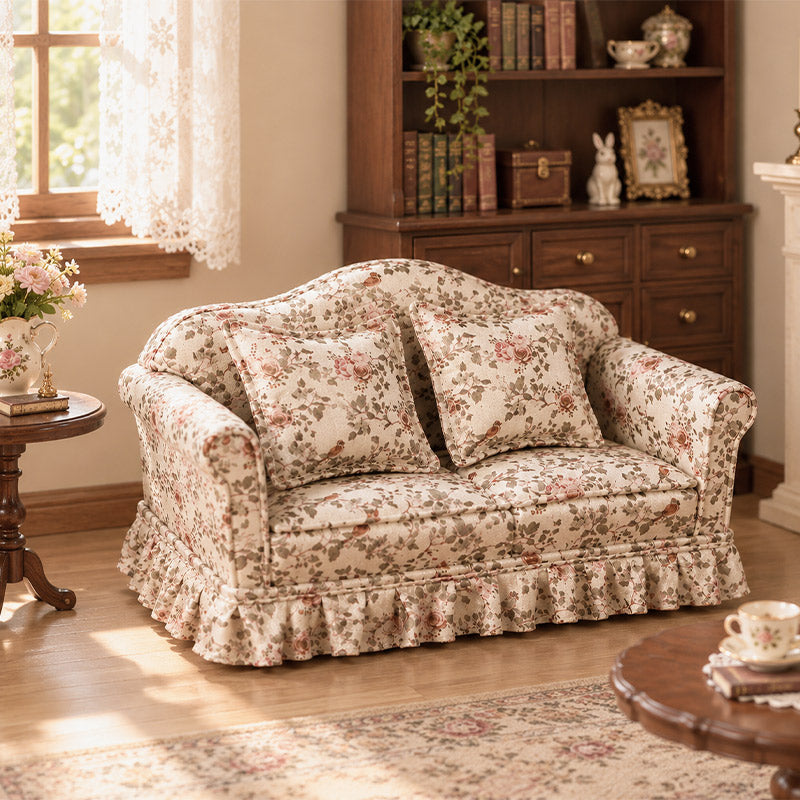 Floral two-seater sofa styled with a bookcase, side table and tea set in a warm vintage miniature interior