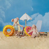 Milo and Pip enjoying a BBQ picnic with miniature beach accessories on the sand.