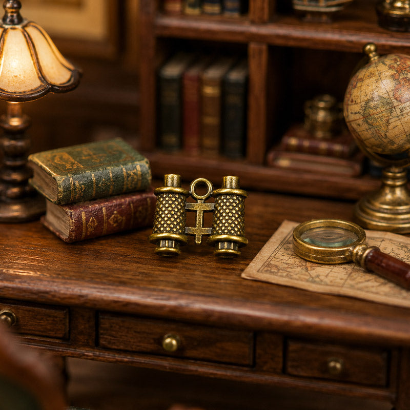 Antique bronze binoculars styled with old books, a globe, and magnifying glass on a cozy miniature study desk.