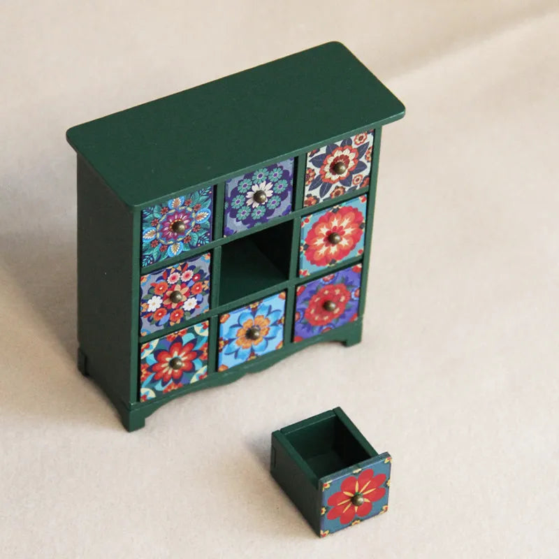 Green wooden cabinet with a removable floral drawer, adding playful storage detail to a charming miniature room