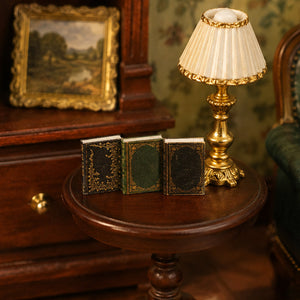 Three ornate miniature books beside a glowing table lamp, styled for a vintage magic library or reading corner