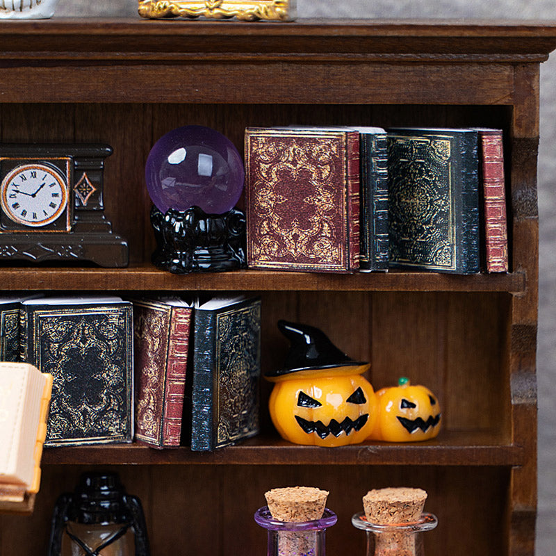 Vintage miniature books styled with a crystal ball and pumpkins for a cozy witch’s study or Halloween library