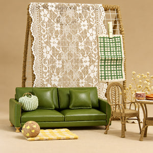 Handmade green PU sofa styled with a plaid throw, wooden coffee table and colorful rug for a cozy Christmas dollhouse scene