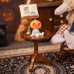 Brown wooden pedestal table styled with an open book and tiny figure for a warm vintage dollhouse reading corner