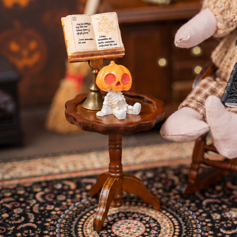 Brown wooden pedestal table styled with an open book and tiny figure for a warm vintage dollhouse reading corner