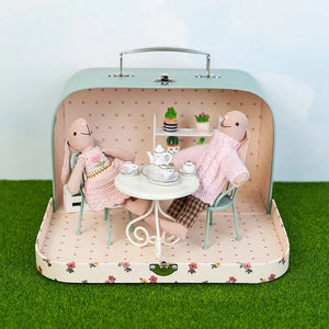 Portable miniature room box opened outdoors with dollhouse furniture creating a playful garden story scene