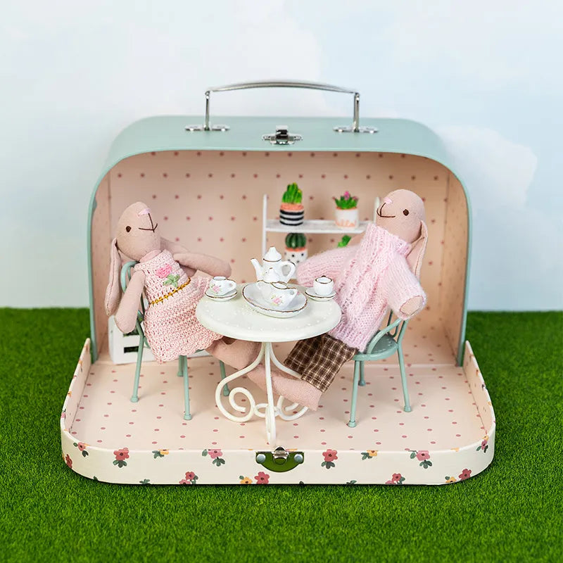 Portable miniature room box opened outdoors with dollhouse furniture creating a playful garden story scene