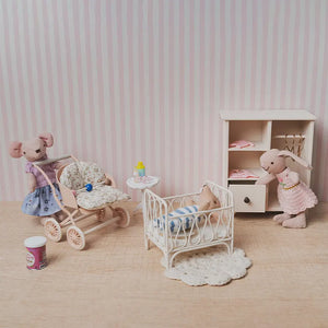dollhouse nursery scene with crib stroller wardrobe and miniature figures in a soft pink 1:12 scale storytelling setup.