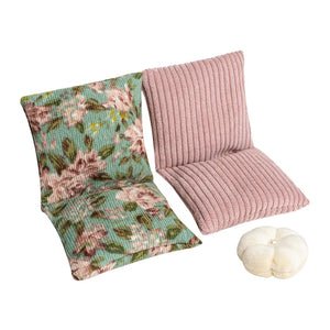 Dollhouse floor sofa with vintage floral fabric and white pillow, creating a cozy miniature sitting space
