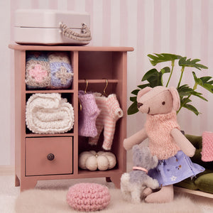 Dusty rose miniature wardrobe filled with knitted clothes and accessories for a cozy dollhouse dressing corner