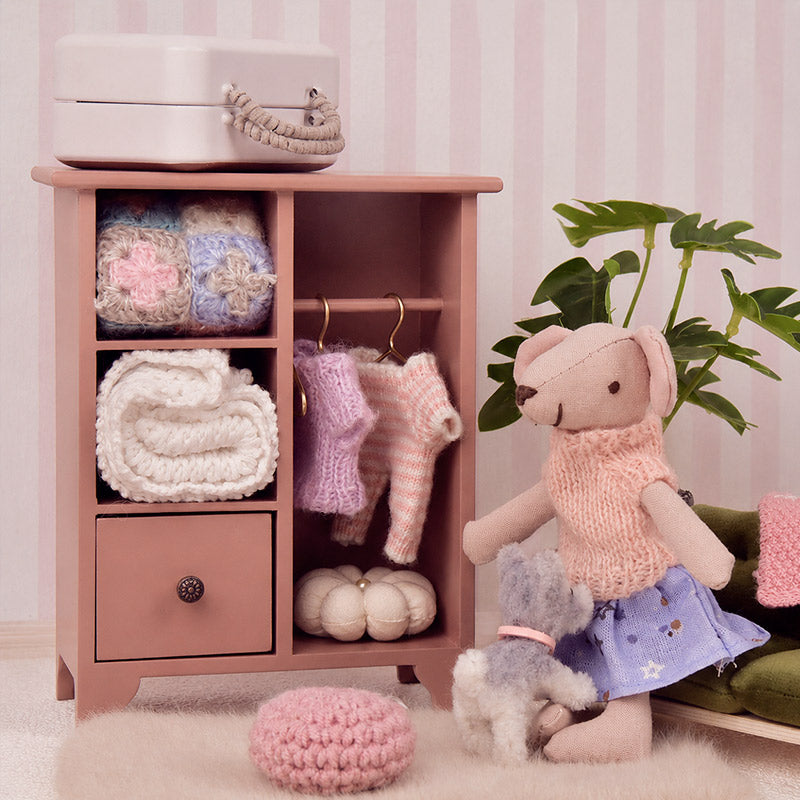 Dusty rose miniature wardrobe filled with knitted clothes and accessories for a cozy dollhouse dressing corner