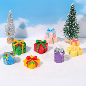 Colorful miniature Christmas presents arranged on snowy ground between frosted trees for a magical winter holiday scene