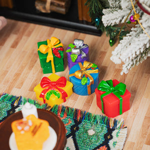 Tiny Christmas gift decorations arranged beside a snowy tree and cozy fireplace, ready for a joyful holiday morning