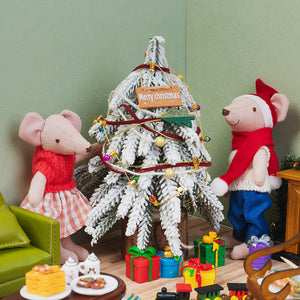 Miniature Merry Christmas hanging sign decorating a snowy Christmas tree as two little mice gather beside colorful gifts.