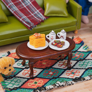 Vintage miniature wooden coffee table styled with tiny desserts and mugs beside an olive green sofa for cozy gatherings