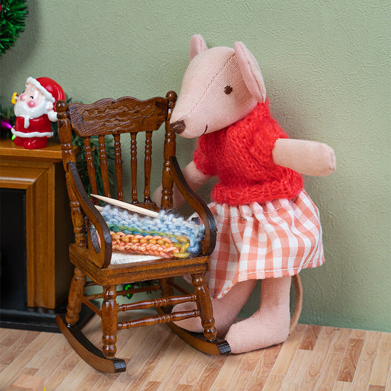 Handmade mouse doll beside a wooden rocking chair with tiny knitting, creating a heartwarming Christmas living room scene.